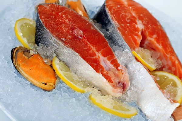 Bitar av röd fisk på isen i plattan isolerad på vit — Stockfoto