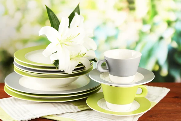 Platos y vasos vacíos sobre mesa de madera sobre fondo verde — Foto de Stock