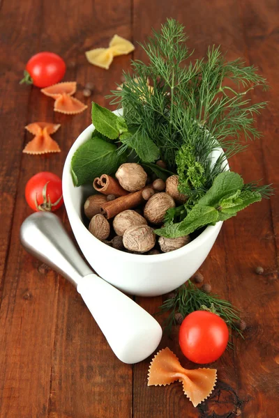 Herbes et épices en mortier céramique, sur fond bois — Photo