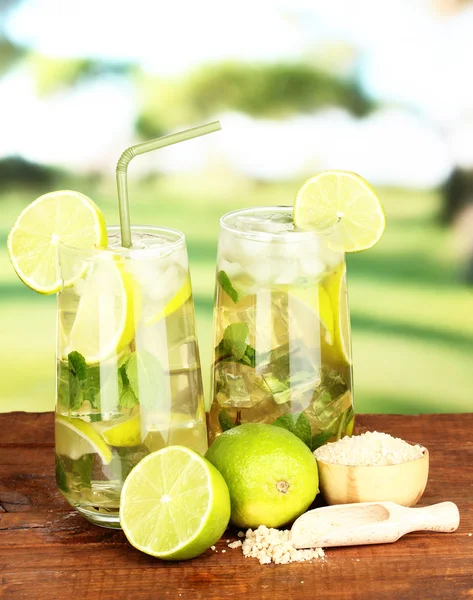 Glasses of cocktail with lime and mint on wooden table on bright background — Stock Photo, Image