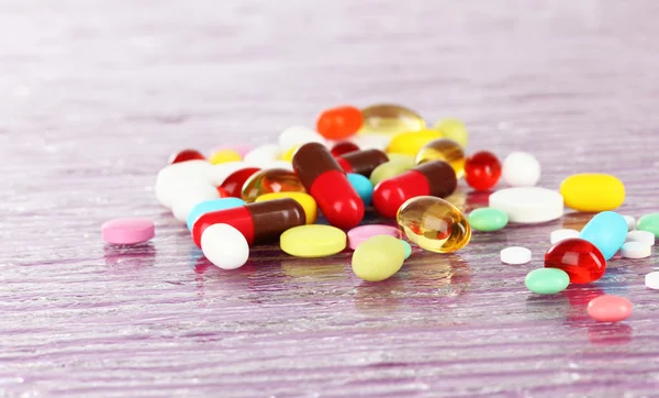 Pillereiden, tablettien ja kapseleiden valikoima violetilla pohjalla — kuvapankkivalokuva