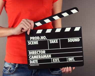 Film üretim clapper panosundaki gri arka plan üzerinde eller