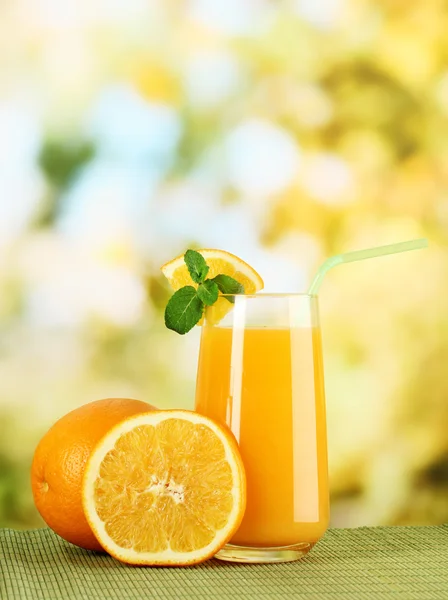 Glass of orange juice with mint and orange on table on bright background — Stock Photo, Image