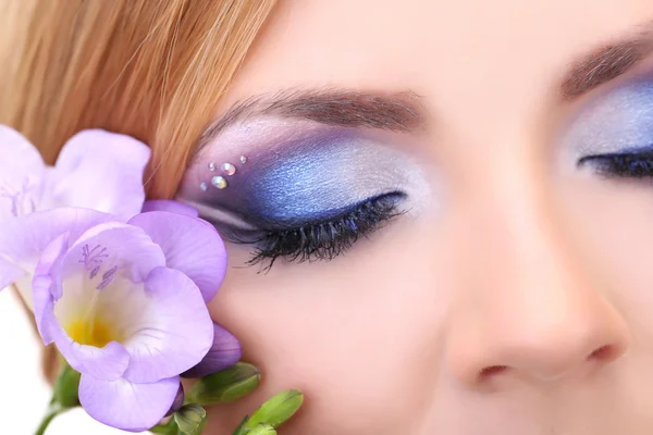 Vackra kvinnliga ögon med ljusa blå make-up och blomma — Stockfoto