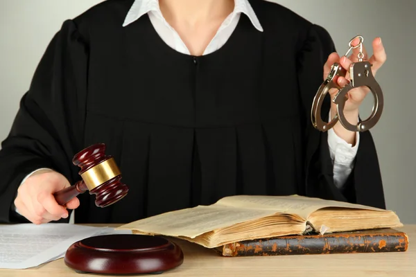 Judge sitting at table during court hearings on grey background — Stock Photo, Image