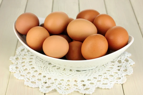 Huevos en tazón blanco sobre mesa de madera de cerca — Foto de Stock