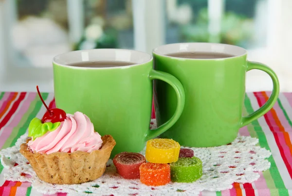 Tazas de té con pastel y dulces en la mesa en la habitación —  Fotos de Stock