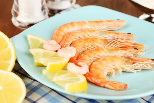 Shrimps with lemon on plate on wooden table close-up — Stock Photo, Image