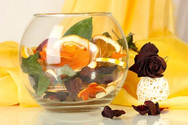 Decorative rose from dry orange peel in glass vase on yellow fabric background — Stock Photo, Image