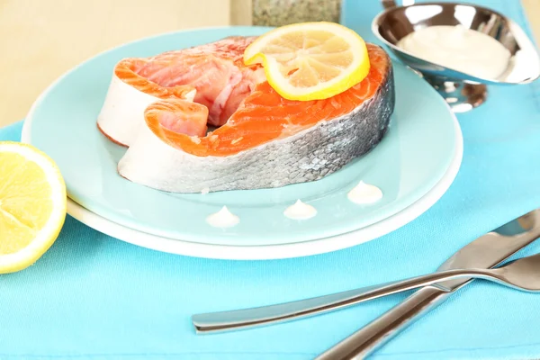 Stück roter Fisch auf Teller mit Gewürzen und Soße auf Holztisch in Großaufnahme — Stockfoto