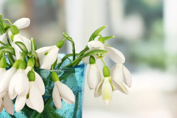 Boeket van snowdrop bloemen in glazen vaas, op lichte achtergrond — Stockfoto