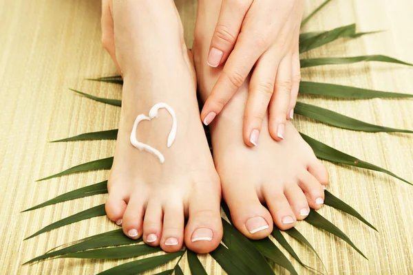 Beautiful woman legs with cream, on bamboo mat — Stock Photo, Image