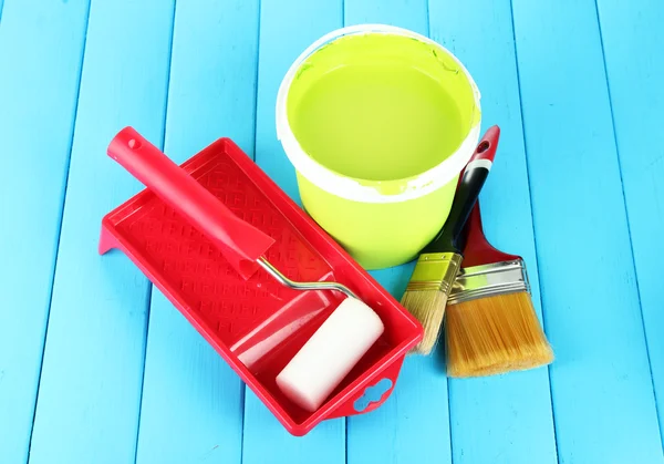 Conjunto para pintura: panela de pintura, pincéis, rolo de pintura em mesa de madeira azul — Fotografia de Stock