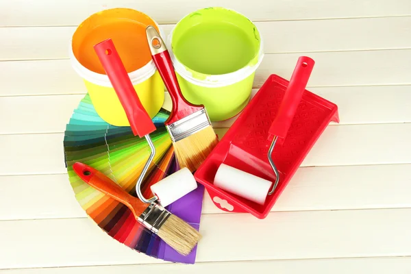 Για ζωγραφική: χρώμα δοχεία, βούρτσες, roller-χρώμα στο λευκό ξύλινο τραπέζι — Φωτογραφία Αρχείου