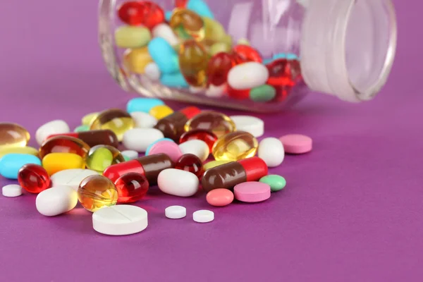 Assortment of pills, tablets and capsules on purple background — Stock Photo, Image