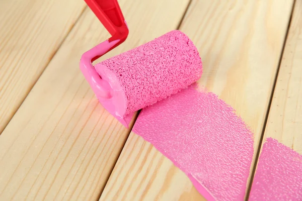 Paint roller brush with pink paint, on wooden background — Stock Photo, Image