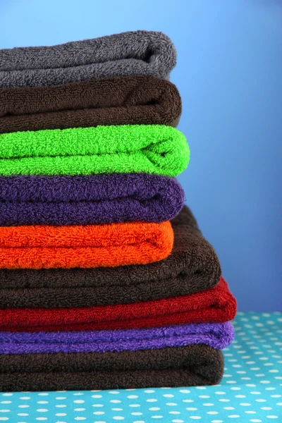 Stapel van kleurrijke handdoeken, op blauwe achtergrond — Stockfoto