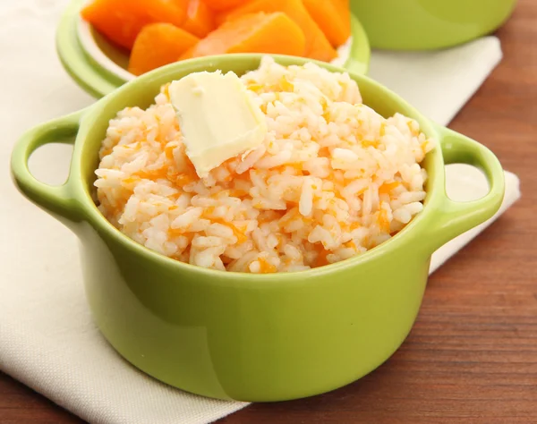 Taste rice porridge with pumpkin in saucepans on wooden backgroun — Stock Photo, Image