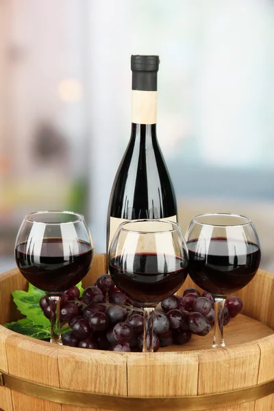 Σύνθεση των μπουκαλιών κρασιού, ποτήρια και σταφυλιών, σε ξύλινο δίσκο, σε φωτεινό φόντο — Φωτογραφία Αρχείου