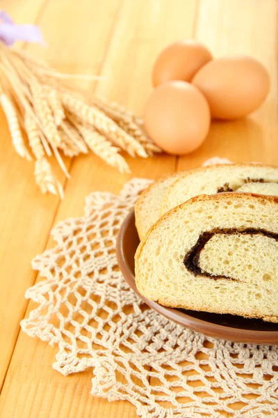 Loaf with poppy seeds on color plate, on wooden background — Stock Photo, Image