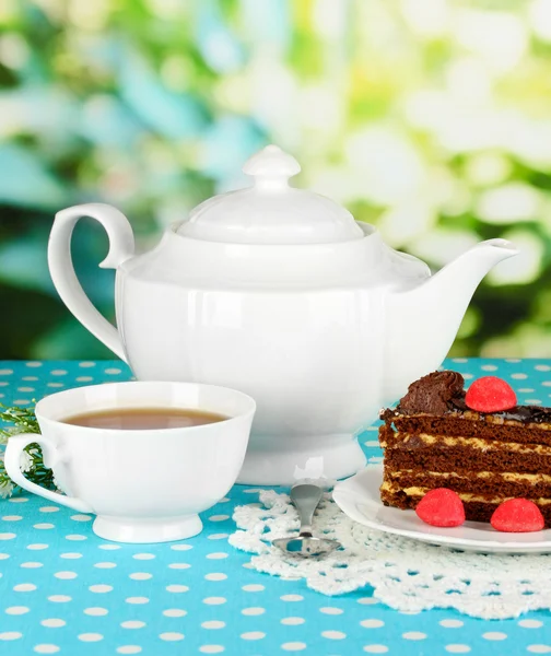 Teapot, cup of tea and delicious cake on natural background — Stock Photo, Image