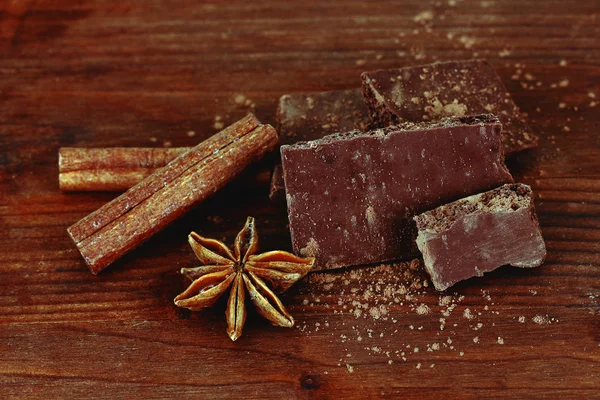 Нарезанный шоколад с какао, специями, на деревянном фоне — стоковое фото