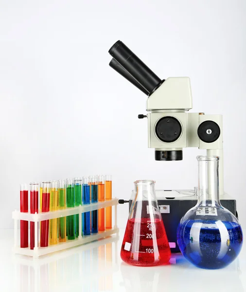 Test tubes with colorful liquids and microscope isolated on white — Stock Photo, Image