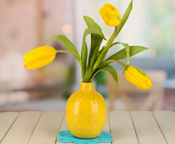 Tulipas amarelas em vaso na mesa de madeira no fundo do quarto — Fotografia de Stock