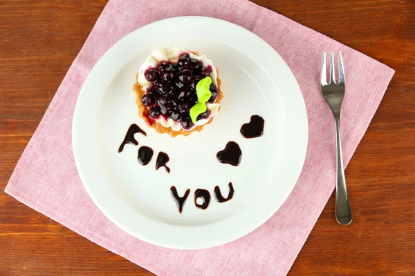 Gâteau sucré à la mûre et sauce au chocolat sur assiette, sur fond bois — Photo