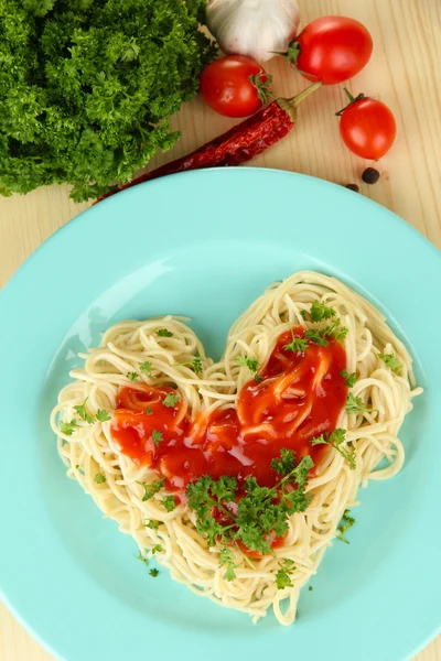 Gotowane spaghetti starannie ułożone w kształcie serca i polane sosem pomidorowym, na tle drewniane — Zdjęcie stockowe