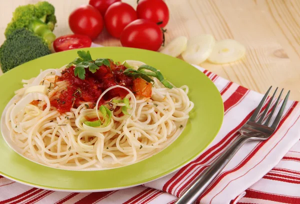 Tasty spaghetti with sauce and vegetables on plate on wooden table close-up — Stock Photo, Image