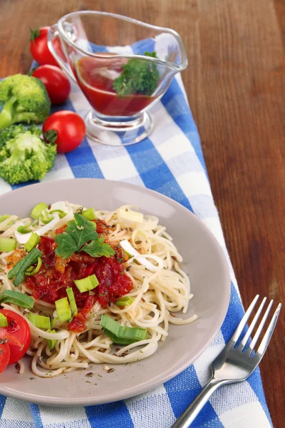 Sabroso espagueti con salsa y verduras en el plato en la mesa de madera de cerca —  Fotos de Stock