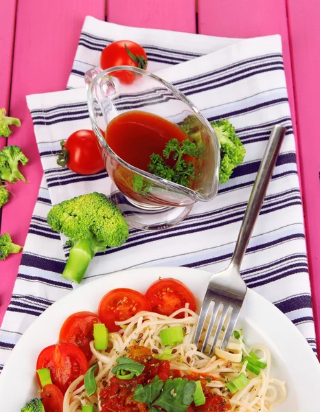 Leckere Spaghetti mit Sauce und Gemüse auf Teller auf Holztisch in Großaufnahme — Stockfoto