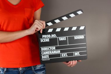 Film üretim clapper panosundaki gri arka plan üzerinde eller