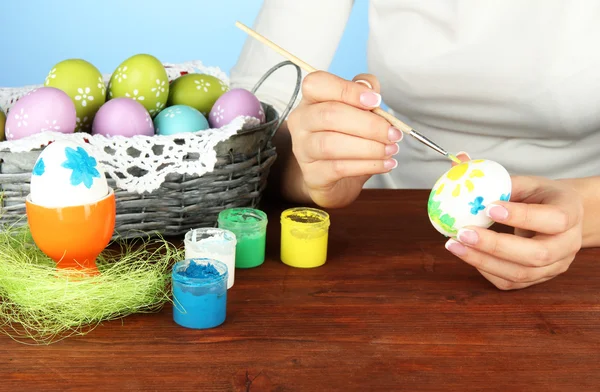 Mujer joven pintando huevos de Pascua, sobre fondo de color — Foto de Stock