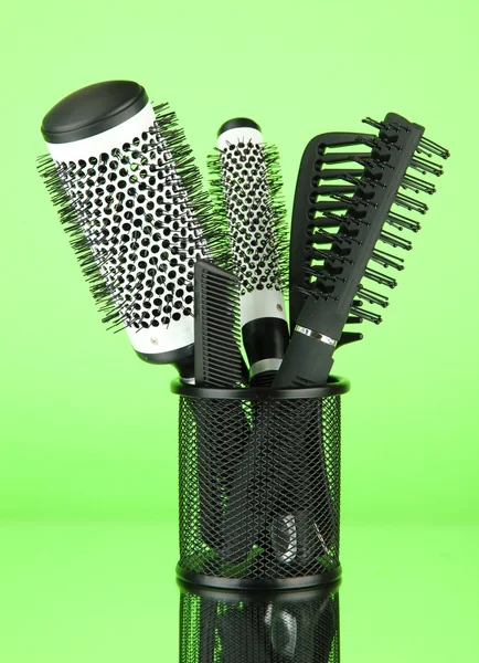 Cesto di ferro con pettini e spazzole rotonde per capelli, su sfondo colore — Foto Stock