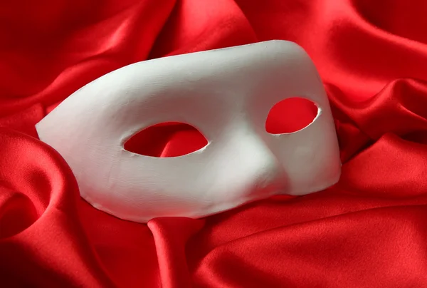 White mask, on red silk fabric — Stock Photo, Image