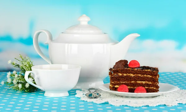 Teekanne, Tasse Tee und leckerer Kuchen auf blauem Hintergrund — Stockfoto