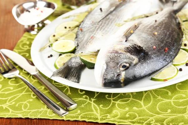 Two fish dorado with lemon on plate on wooden table close-up — Stock Photo, Image