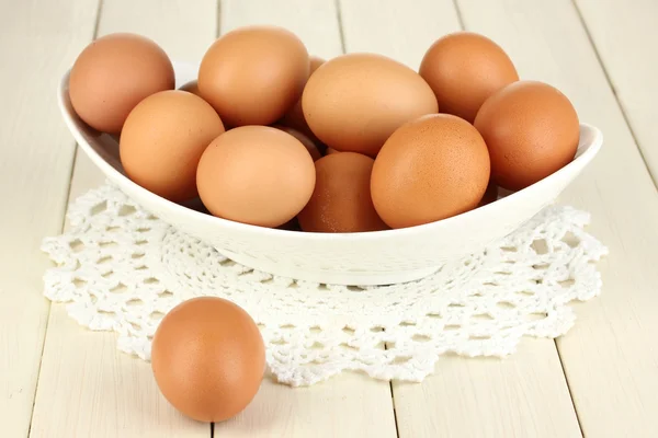 Eier in weißer Schüssel auf Holztisch in Großaufnahme — Stockfoto