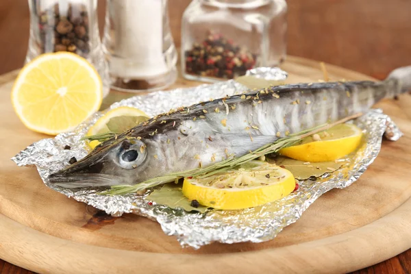 Ryba w folii z ziołami i cytryną na pokładzie na drewniany stół szczegół — Zdjęcie stockowe