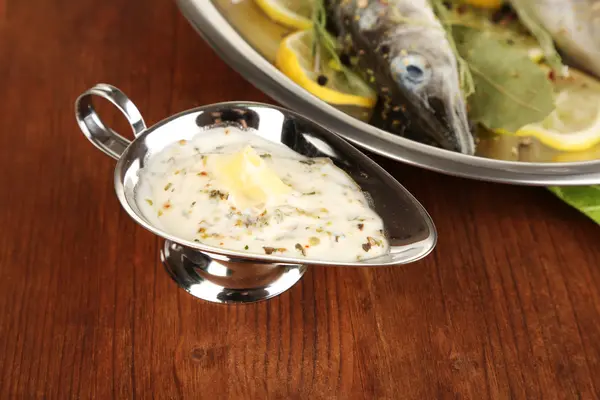 Fisch in Pfanne mit Gewürzen und Zitrone auf Holztisch in Großaufnahme — Stockfoto