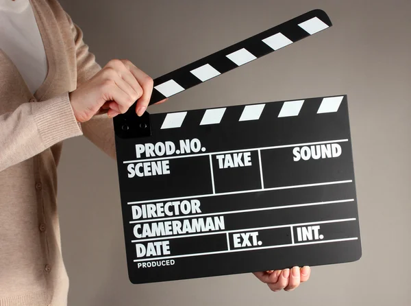Produção de filmes clapper board em mãos sobre fundo cinza — Fotografia de Stock