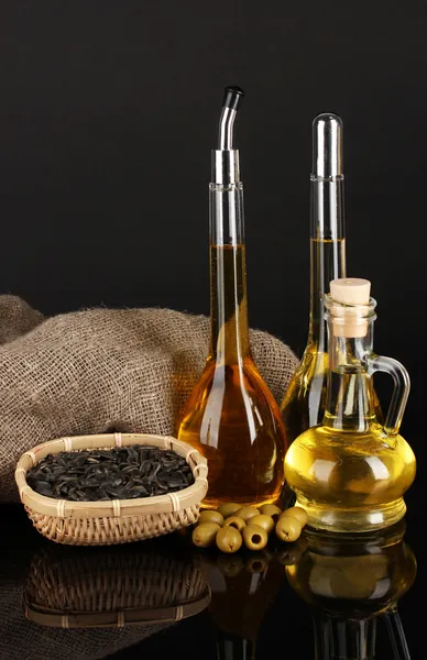 Different types of oil with sunflower seeds and olives on dark background — Stock Photo, Image