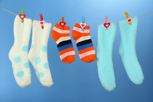 Colorful socks hanging on clothesline, on color background — Stock Photo, Image