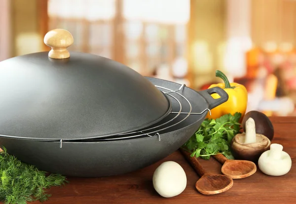 Czarny pan woka i warzywa na drewnianym stole w kuchni, z bliska — Zdjęcie stockowe