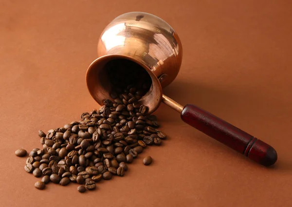 Panela de café com grãos de café no fundo marrom — Fotografia de Stock