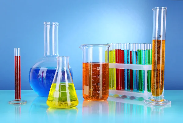 Reageerbuisjes met kleurrijke vloeistoffen op blauwe achtergrond — Stockfoto