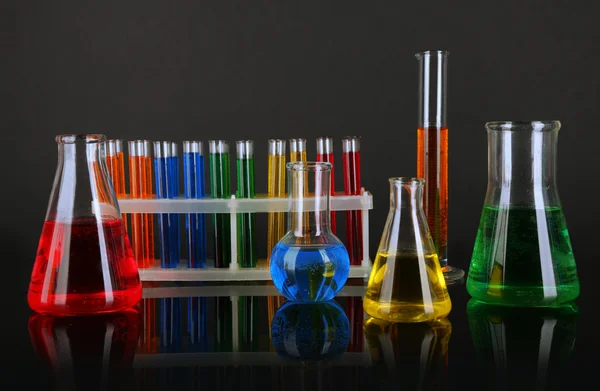 Test tubes with colorful liquids on dark grey background — Stock Photo, Image