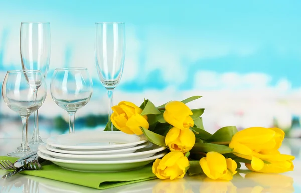 Yellow tulips and utensils for serving on blue natural background background — Stock Photo, Image